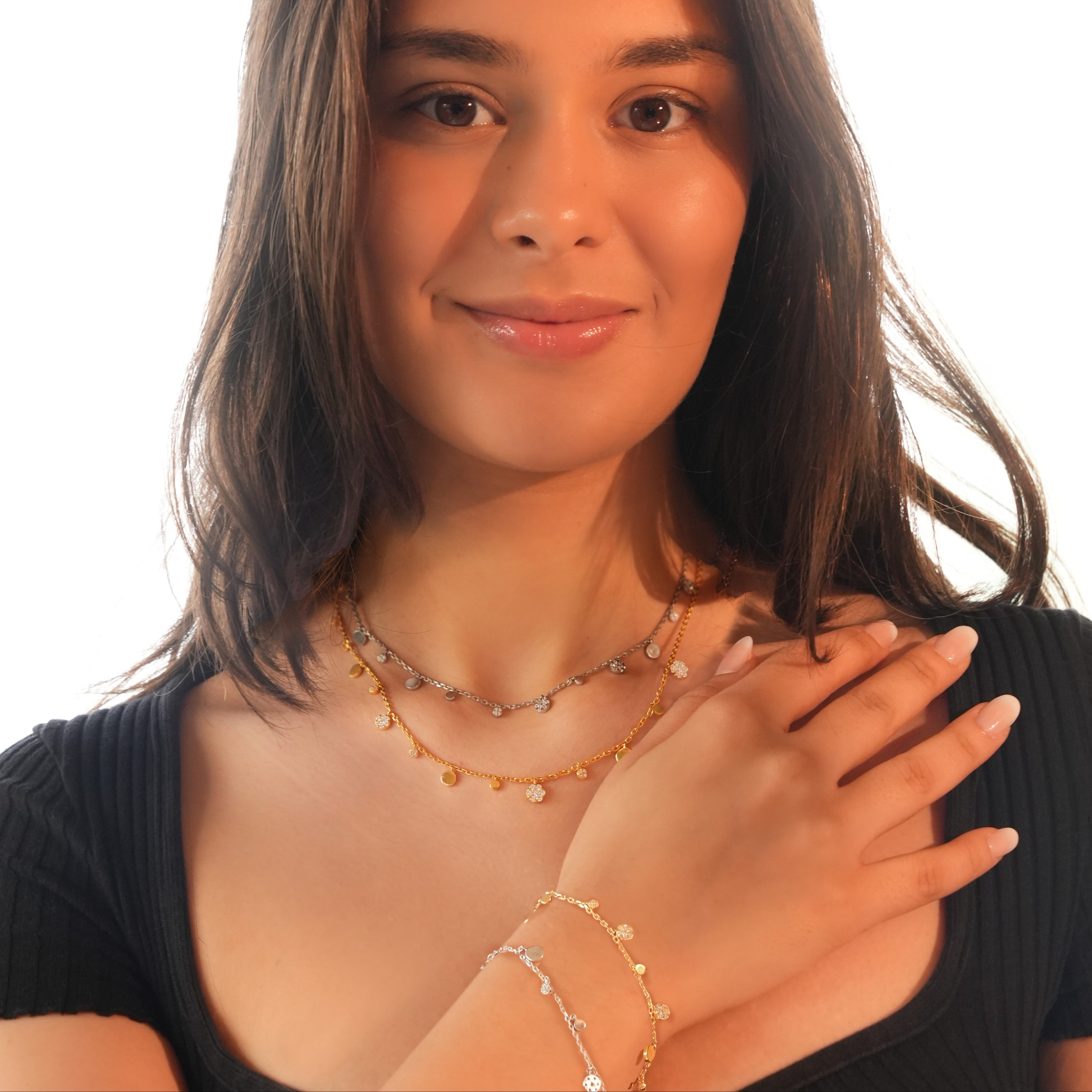 Model wearing circe dangle bracelets stacked together in gold tone and silver tone finishes